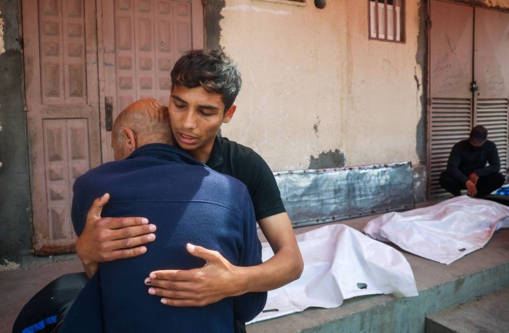 Relatives mourn by the bodies of three Palestinian men who were killed in an Israeli drone strike east of the Bureij camp, at the al-Aqsa Martyrs hospital in Deir el-Balah in the central Gaza Strip on Monday. AFP