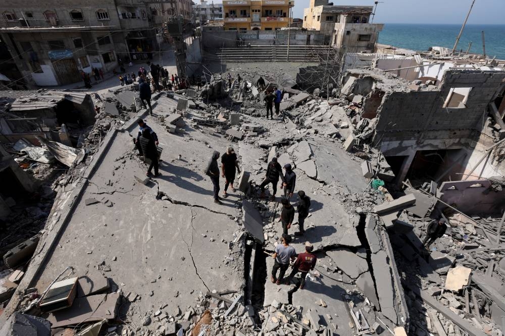 Palestinians inspect the site of an Israeli strike on a residential building, in Deir Al-Balah in the central Gaza Strip, on Tuesday. REUTERS