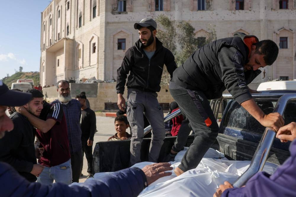 Palestinians mourn around bodies wrapped in white shrouds in the back of a truck, after Israel unleashed a wave of deadly overnight strikes on the Gaza Strip, as they are transported from the Indonesian Hospital in Beit Lahia in northern Gaza for burial, on Tuesday. AFP