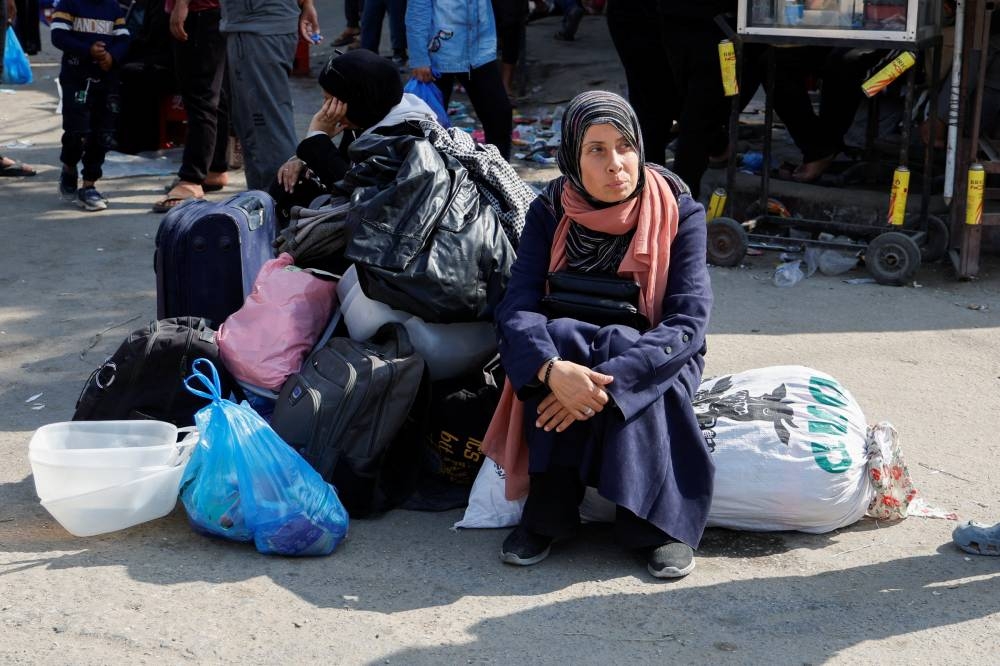 A woman sits on belongings as Palestinians make their way to flee their homes, in Rafah in the southern Gaza Strip, on Tuesday. REUTERS