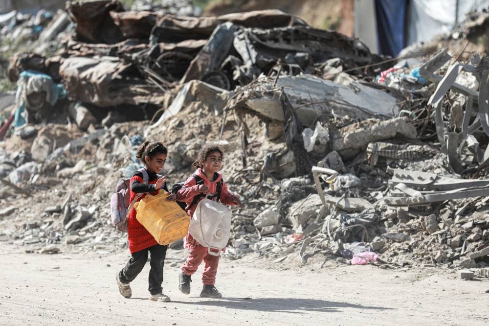 Palestinian children walk past rubble as people make their way to flee their homes, after the Israel army issued evacuation orders for a number of neighborhoods, following heavy Israeli strikes, in Beit Lahiya in the northern Gaza Strip, on Tuesday. REUTERS