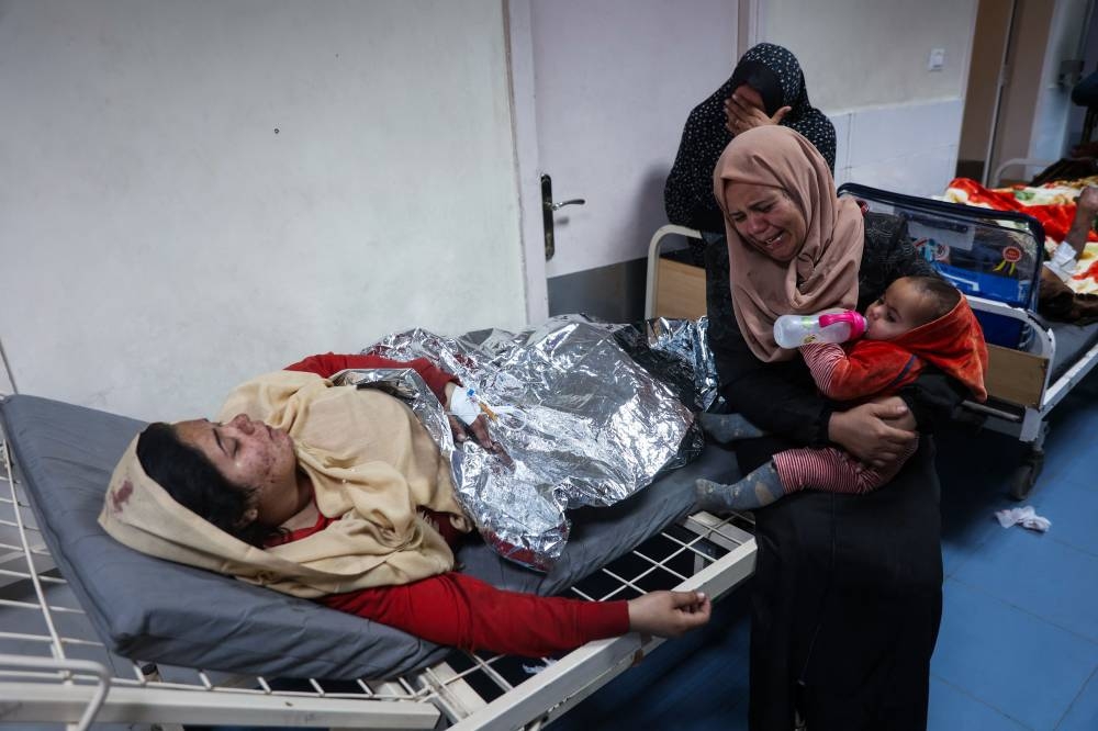 A woman cries next to her relative, injured in an Israeli strike, at Al-Mamdani Hospital in Gaza City on Tuesday. AFP