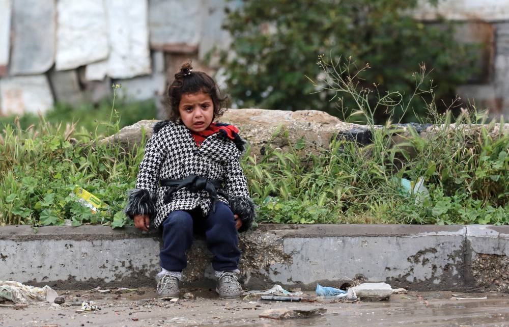 A young girl sits crying on the side of a road as Palestinians flee with their belongings Beit Lahia in the Northern Gaza Strip on Friday. AFP