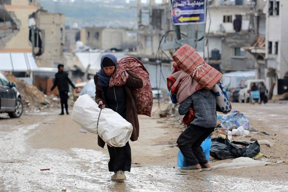 A Palestinian woman carries her belongings as she flees Beit Lahia in the northern Gaza Strip on Friday. AFP