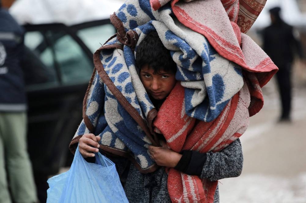 A Palestinian youth carries blankets as he flees Beit Lahia in the Northern Gaza Strip on Friday. AFP