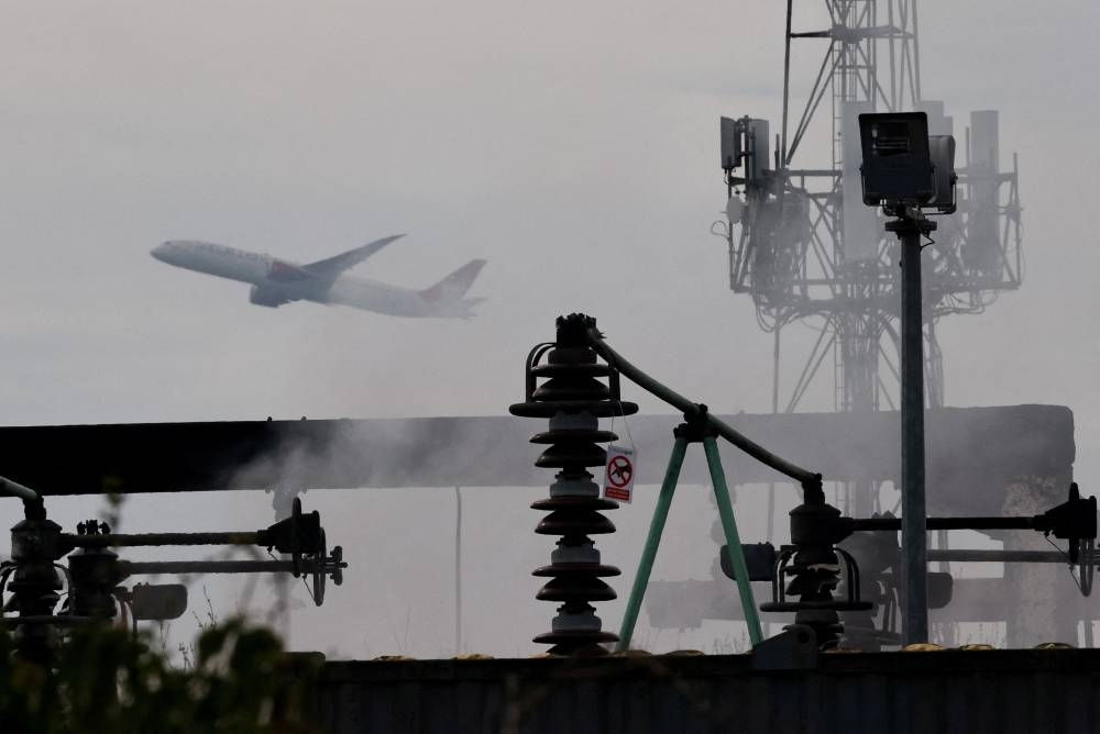 A plane takes off, as smoke rises from an area of an electrical substation a day after it caught fire and wiped out power at Heathrow International Airport, near London,, on Saturday. REUTERS