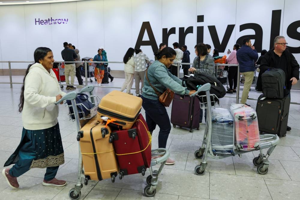 People with luggage arrive at Terminal 4 of the Heathrow International Airport, a day after a fire at a nearby electrical substation wiped out the power at the airport, near London, on Saturday. REUTERS