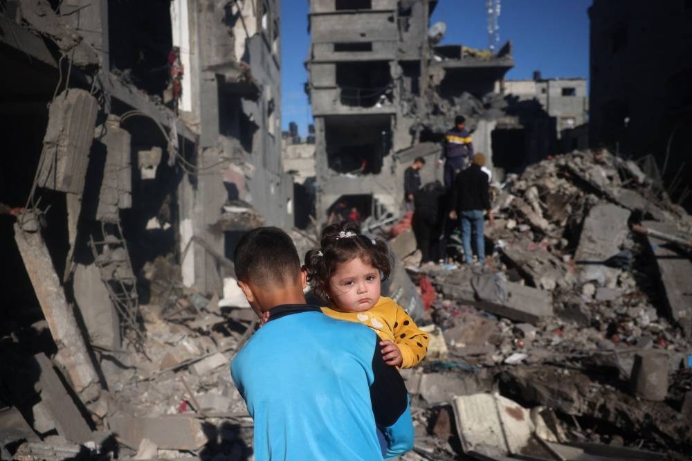 TOPSHOT - Palestinian children react as they inspect the rubble and debris at the site of Israeli strikes the night before at the Nuseirat refugee camp in the central Gaza Strip, on Sunday. AFP