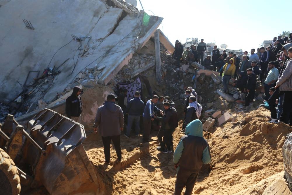 Palestinians search through the rubble of a building at the site of an Israeli strike in Khan Younis in the southern Gaza Strip Sunday.