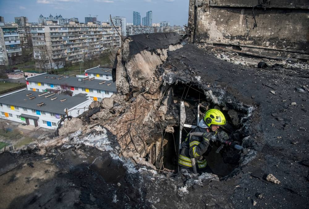 A firefighter works at an apartment building hit by a Russian drone strike, in Kyiv, Ukraine on Sunday.