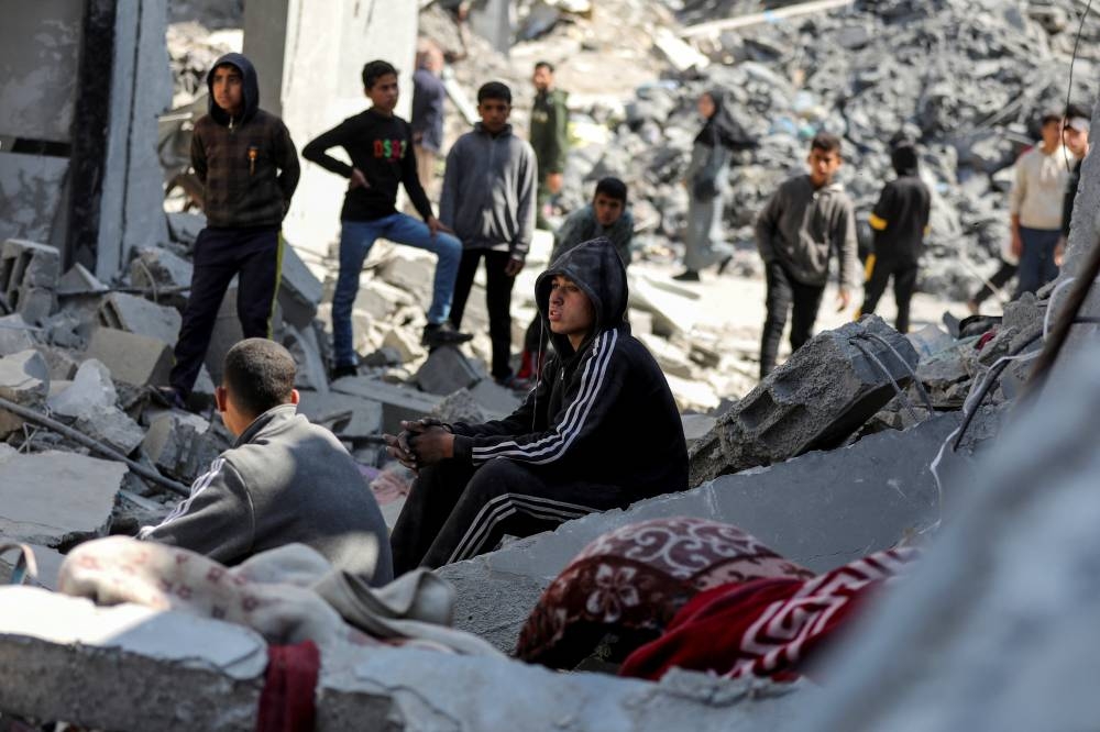 Palestinians gather at the site of an Israeli strike on a house, in Gaza City, on Monday. REUTERS