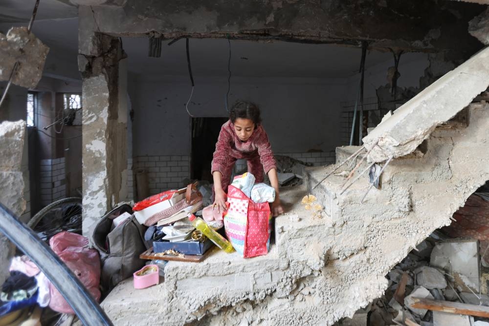 A Palestinian girl gathers her belongings at the site of an Israeli strike on a house, in Bureij, in the central Gaza Strip, on Tuesday. REUTERS