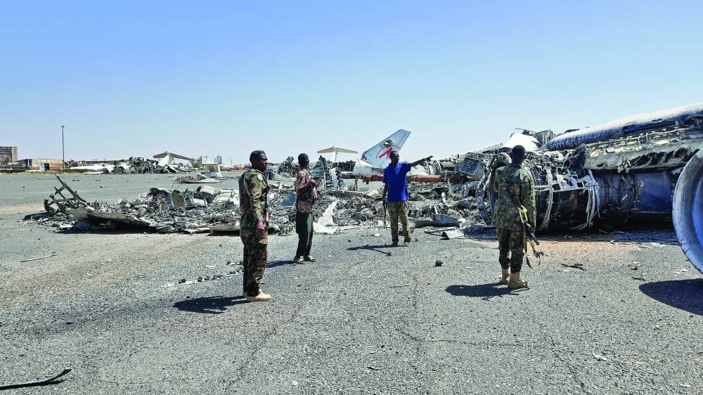 Members of Sudanese army walk next to destroyed planes on the tarmac at Khartoum Airport, on Thursday 