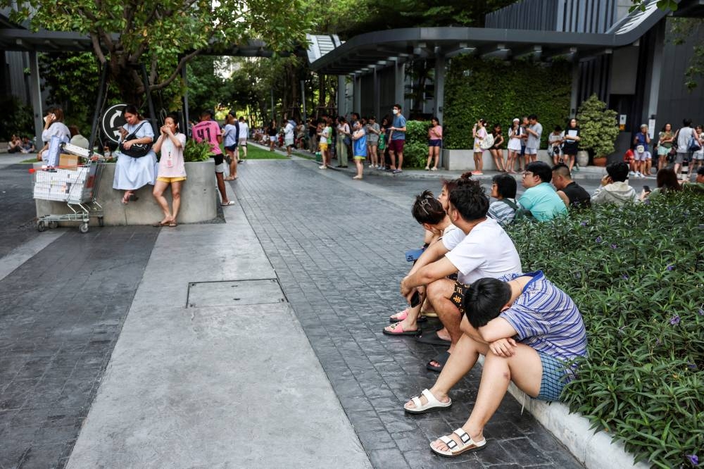 People gather outside a building after a strong earthquake struck central Myanmar on Friday, earthquake monitoring services said, which affected Bangkok as well with hundreds of people pouring out of buildings in the Thai capital in panic after the tremors, in Bangkok, Thailand, on Friday. REUTERS