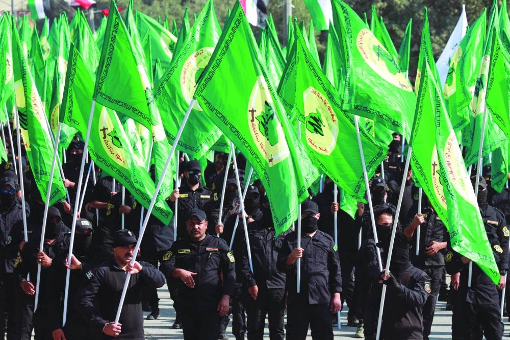Fighters from Iraq's Hashed al-Shaabi (Popular Mobilisation Forces) carry flags as they rally to mark the annual Quds Day (Jerusalem day) commemorations in Baghdad, yesterday.