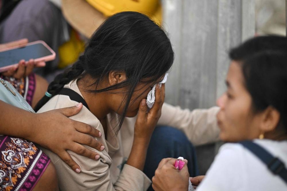 A woman (C) reacts as she waits for news of a missing family member at the site of an under-construction building collapse in Bangkok on Saturday a day after an earthquake struck central Myanmar and Thailand. AFP