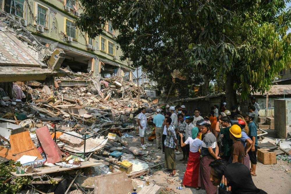 People look on as teams of rescue workers attempt to free residents trapped under the rubble of the destroyed Sky Villa Condominium development in Mandalay on Saturday. AFP