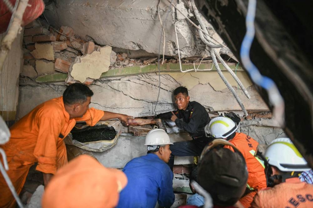 Rescue workers attempt to free a resident trapped under the rubble of the destroyed Sky Villa Condominium development in Mandalay on Saturday. AFP
