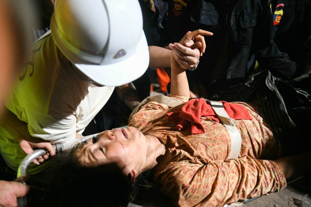 Ye Aung accompanies his wife Phyu Lay Khaing on their way to the hospital after she was rescued from the rubble of the collapsed Sky Villa Condo apartment building in Mandalay on Saturday. AFP
