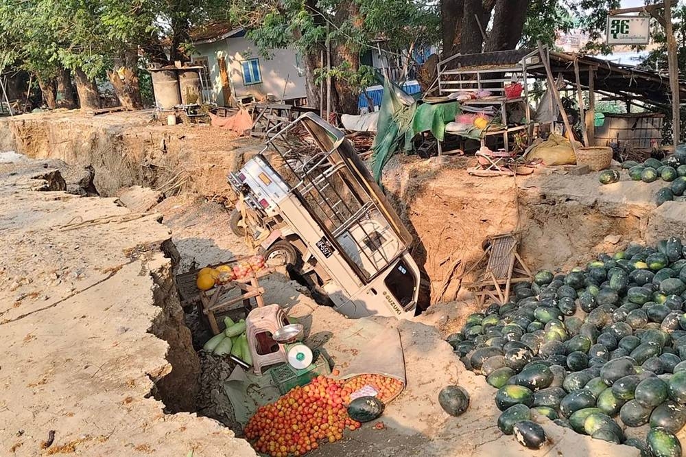 A vehicle stuck in a crack in the ground next to spilled watermelons and vegetables in Sagaing, following an earthquake. AFP PHOTO / Courtesy of Facebook user Hla Myo Aung