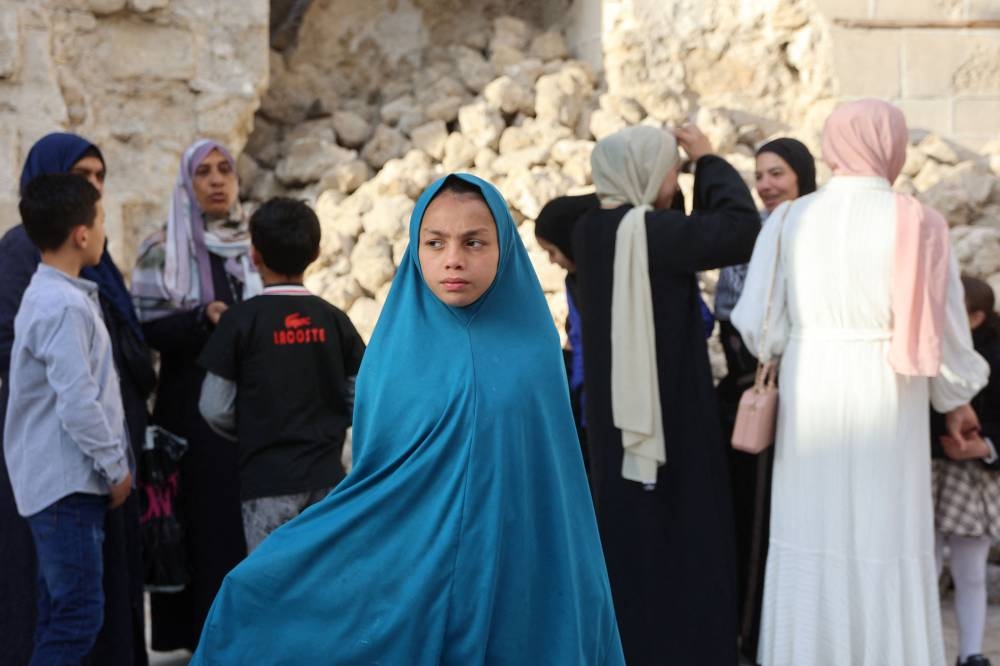 Palestinians arrive to attend Eid al-Fitr prayers, which marks the end of the holy fasting month of Ramadan, at Gaza City's historic Omari Mosque, on Sunday. AFP