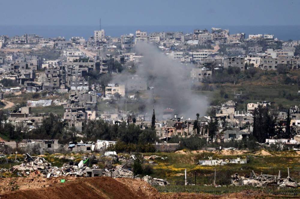 A picture taken from the Israeli side of the border with the Gaza Strip shows a smoke plume rising from explosions above destroyed buildings in the northern Gaza Strip, on Sunday. AFP