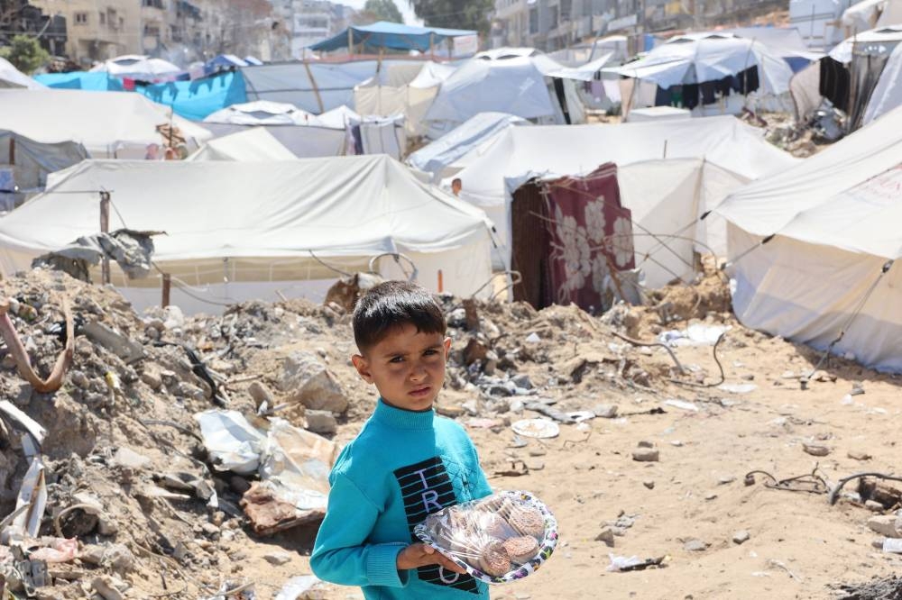 A Palestinian boy carries traditional cookies back to his family during Eid al-Fitr, which marks the end of the holy fasting month of Ramadan, in Gaza City, on Sunday. AFP