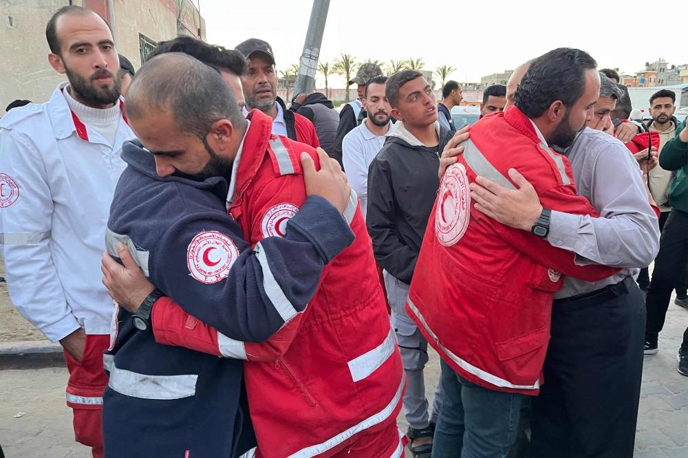 First responders embrace each other at Nasser Medical Complex in Khan Yunis in the southern Gaza Strip on Sunday as the bodies of Palestinian first responders who were killed a week before in Israeli military fire on ambulances arrive at the facility. AFP