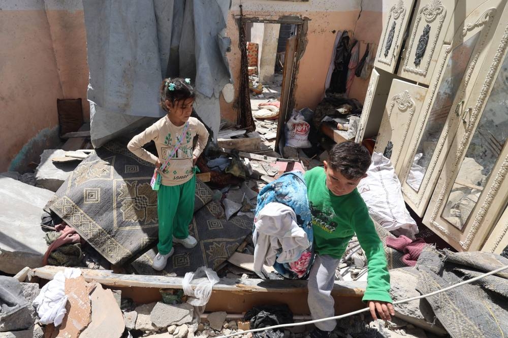 Palestinian children salvage items from the rubble of a house that was destroyed in an Israeli airstrike in Khan Yunis in the southern Gaza Strip, on Monday. AFP