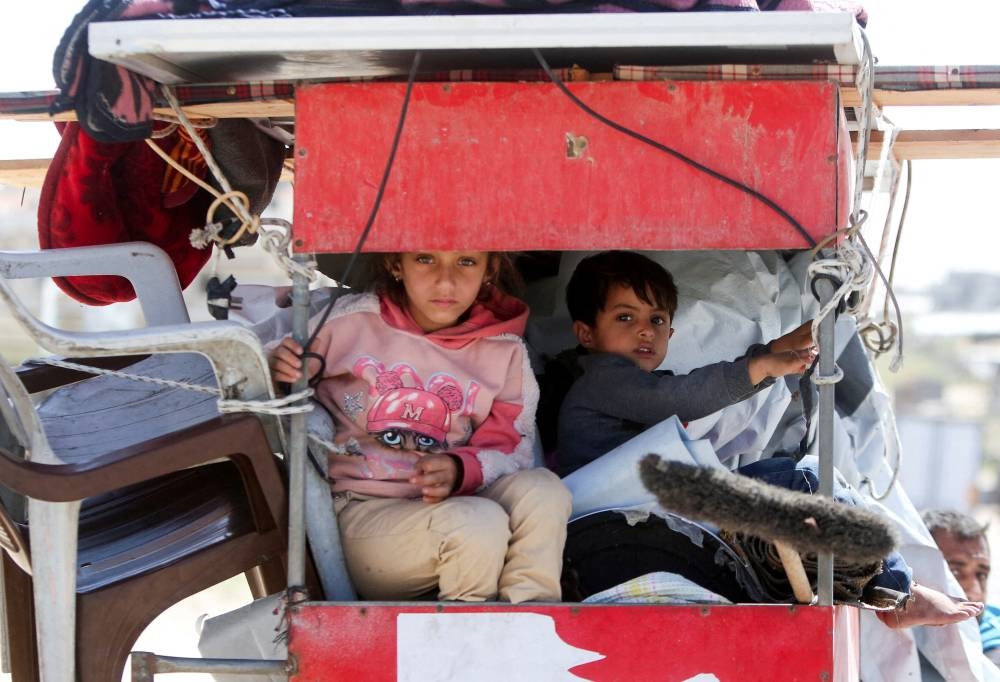 Children look on, as they travel on a vehicle, while Palestinians make their way after fleeing areas around the southern city of Rafah, following an Israeli evacuation order, in Khan Younis in the southern Gaza Strip, on Monday. REUTERS