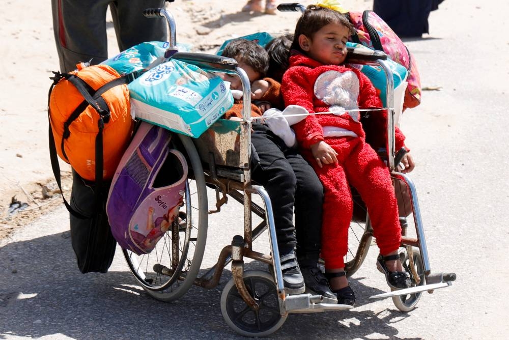 Children rest on a wheelchair, as Palestinians make their way after fleeing areas around the southern city of Rafah, following an Israeli evacuation order, in Khan Younis in the southern Gaza Strip, on Monday. REUTERS