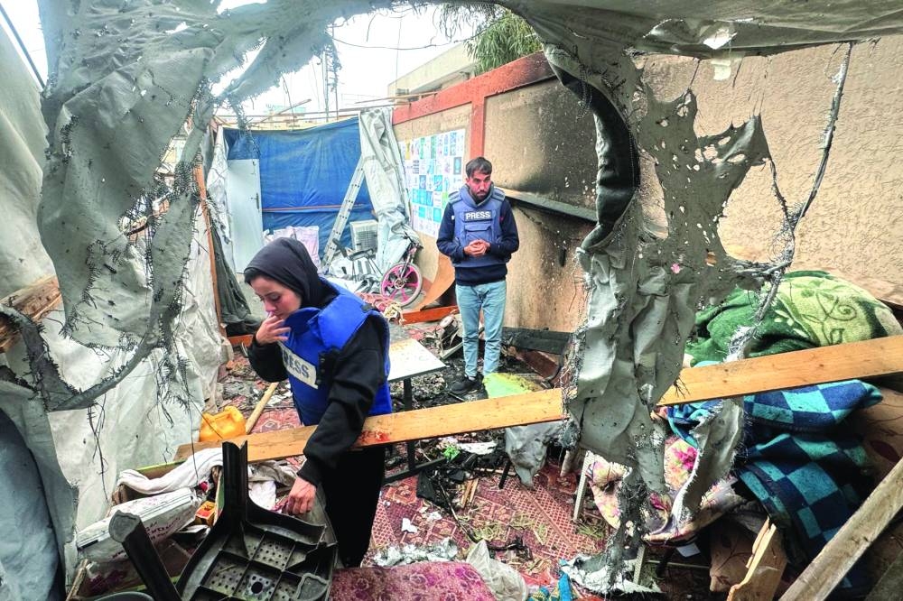 Palestinian journalists inspect the debris and damage after an Israeli strike hit a tent used by journalists in the southern city of Khan Younis on Monday 