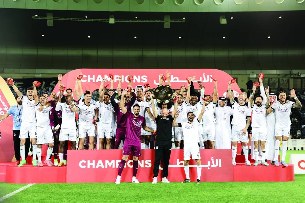 Al Sadd coach Felix Sanches lifts the Falcon Shield as the players and officials celebrate after the Wolves clinched the Qatar Stars League at the Jassim Bin Hamad Stadium on Friday.