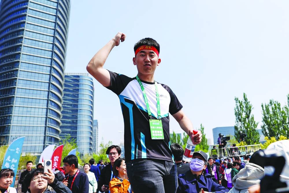 Noetix Robotics founder Jiang Zheyuan cheers for his robot Noetix N2 as it runs towards the finish line in second place during the E-Town Humanoid Robot Half Marathon in Beijing.