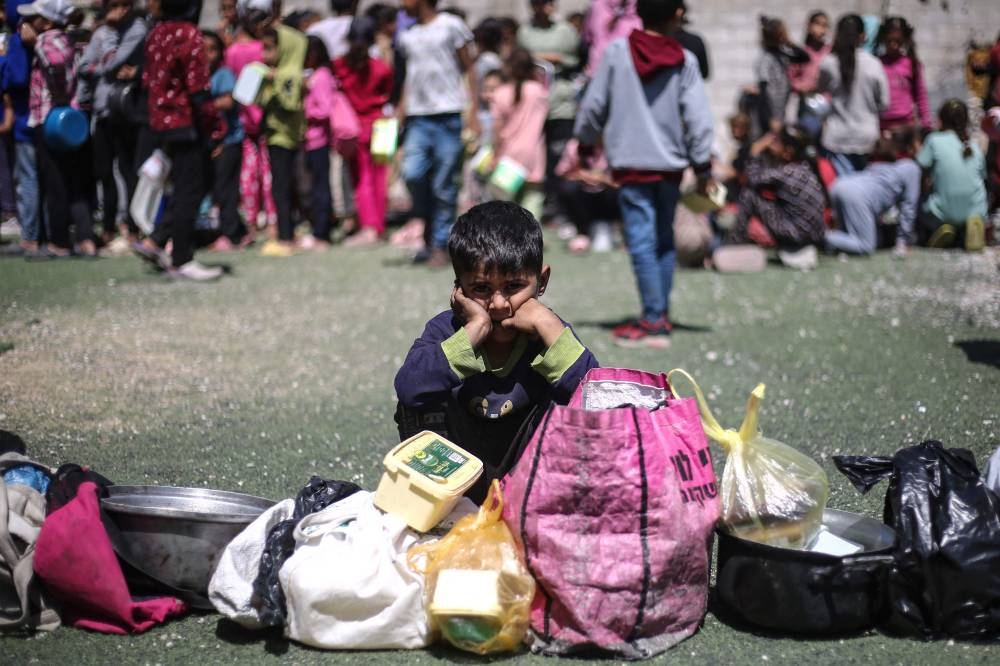A Palestinian child waits to receive a hot meal at a free food distribution point at the Nuseirat refugee camp in the central Gaza Strip on Saturday 