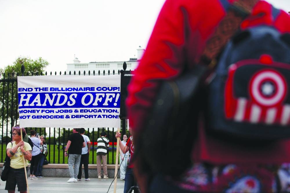 Demonstrators display a 'Hands Off!' banner during a protest yesterday at the White House against US President Donald Trump, tariffs, deportations, a variety of other policies, and Elon Musk, one of many demonstrations taking place nationwide, in Washington, DC. – Reuters