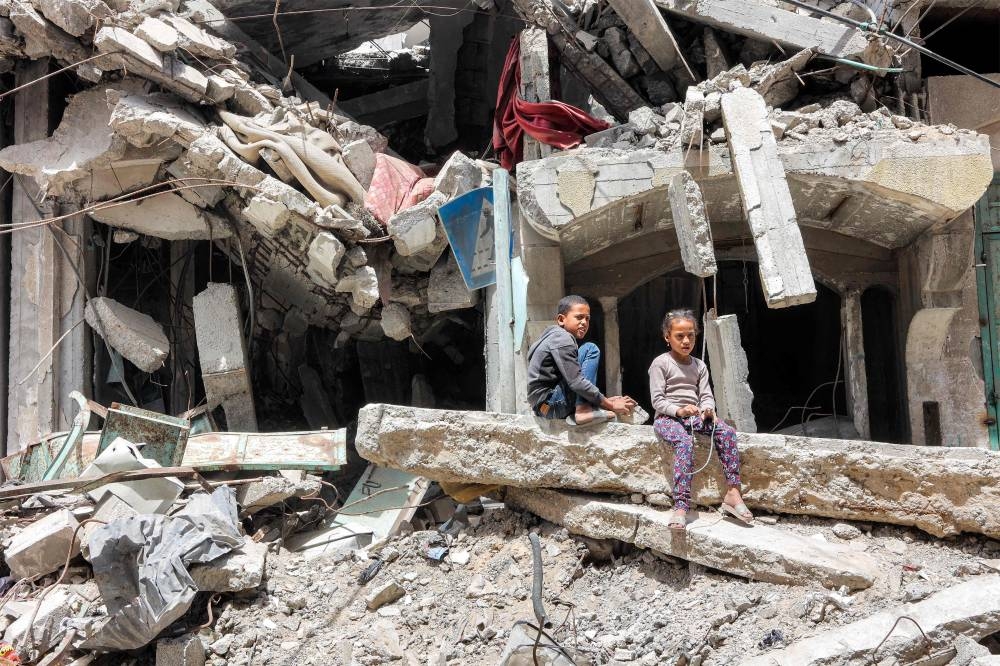 A boy and a girl sit by the ruins of a destroyed building in Gaza City on Monday 