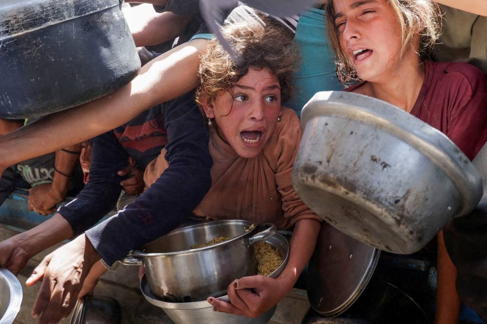 Palestinians gather as they receive food cooked by a charity kitchen, in Khan Younis, southern Gaza Strip, on Tuesday. REUTERS
