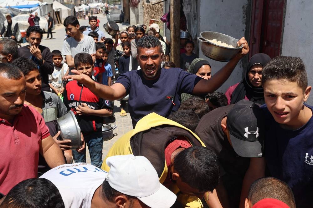 Palestinians gather as they receive food cooked by a charity kitchen, in the Bureij refugee camp in the central Gaza Strip, on Tuesday.  AFP
