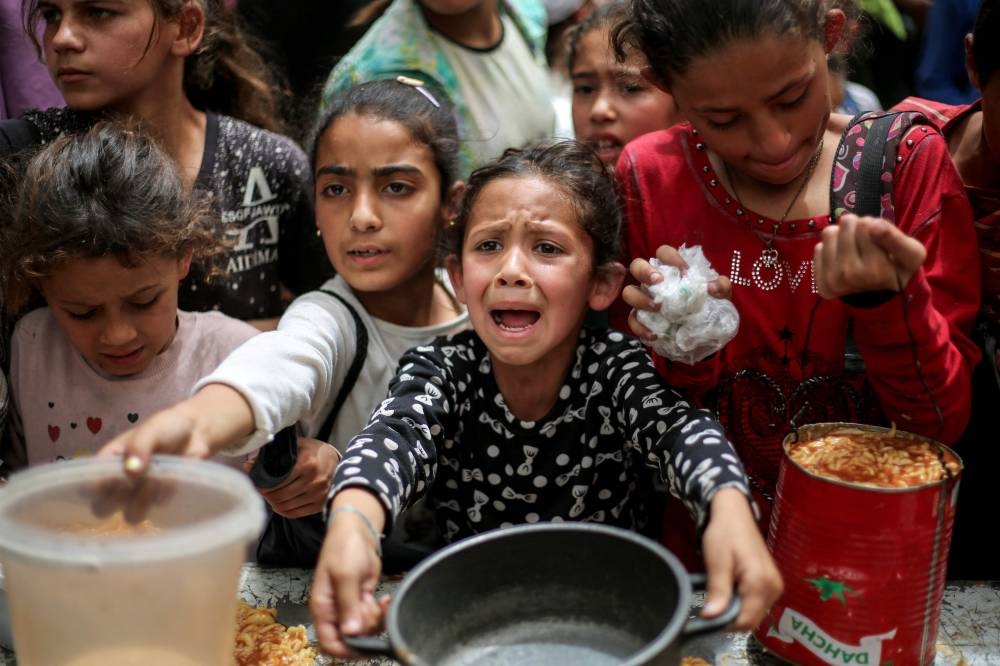 Children gather to receive a hot meal at a food distribution centre in the Nuseirat camp in the central Gaza Strip, Wednesday.