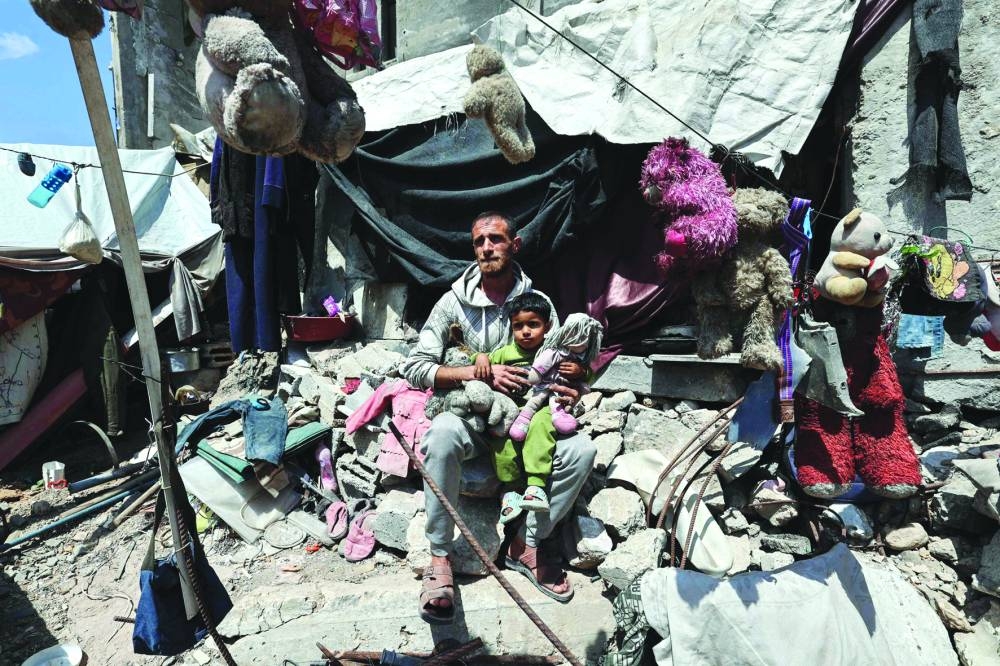 Palestinian father Wissam Wishah who lost three of his children,  in Israeli strikes in the vicinity of their home, sits with his son after hanging their toys and belongings on the rubble of their house at the al-Bureij refugee camp in the central Gaza Strip yesterday
