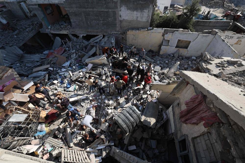 People look for survivors in the rubble of a building hit in an Israeli strike in the Bureij camp for Palestinian refugees in the central Gaza Strip on Friday. AFP