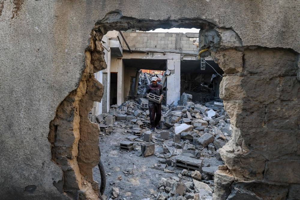 A man carries salvaged concrete blocks inside a building hit in an Israeli strike in the Bureij camp for Palestinian refugees in the central Gaza Strip on Friday. AFP
