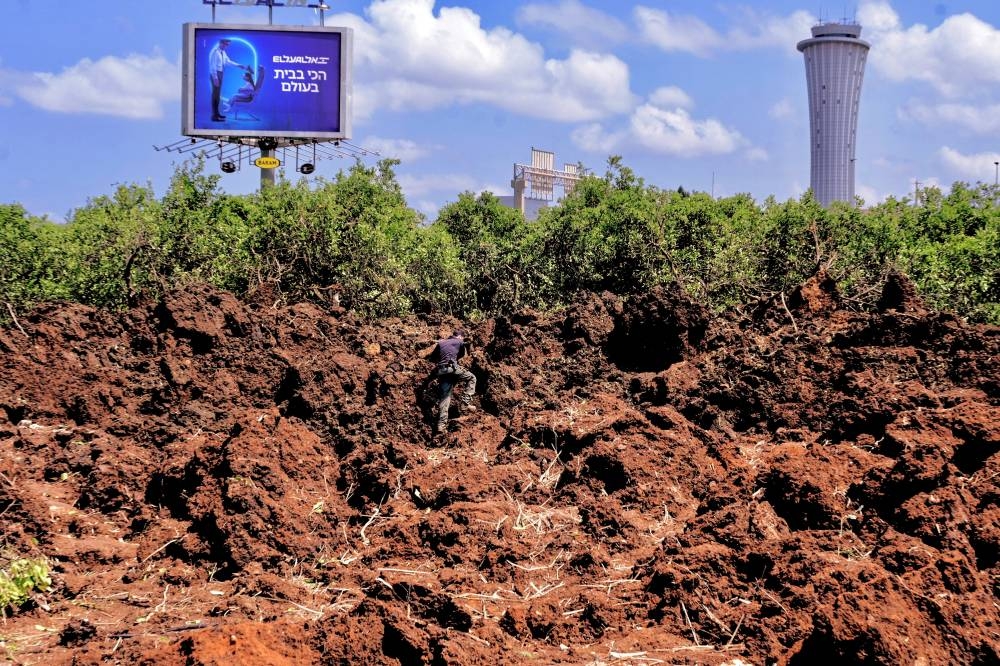 An Israeli police officer investigates a crater at the site of a missile attack, launched from Yemen, near Ben Gurion Airport, in Tel Aviv, on Sunday. REUTERS