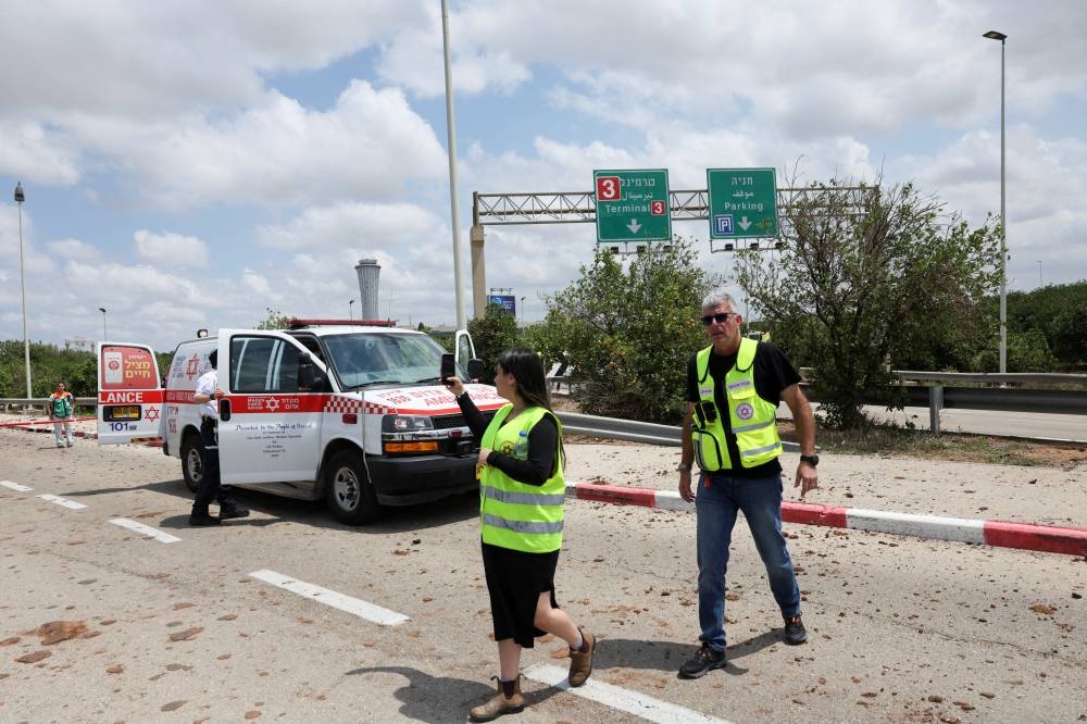 Emergency personnel work at the site of a missile attack, launched from Yemen, at the entrance of Ben Gurion Airport, in Tel Aviv, on Sunday. REUTERS