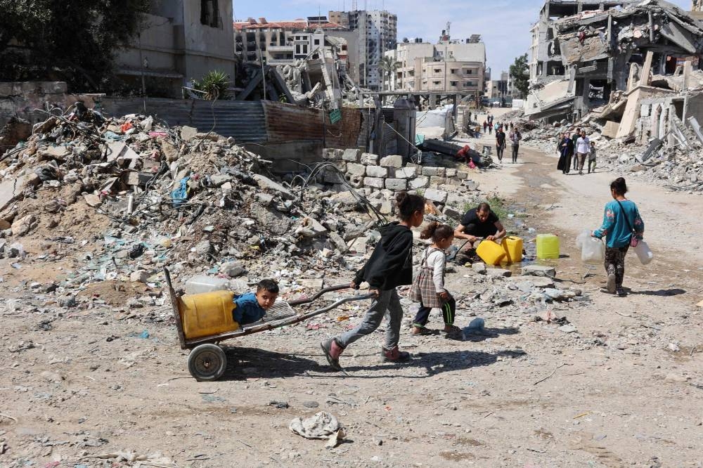 Palestinian children head to a water distribution point to fill their containers in Gaza City on Sunday.