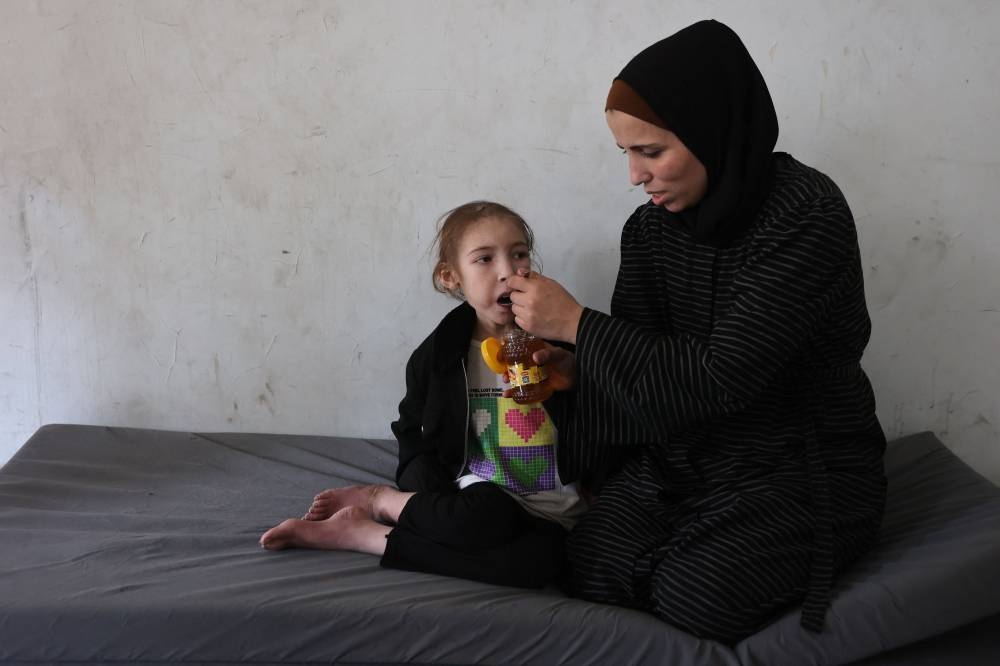 Shuruq Ayyad feeds her 12-year-old daughter Rahaf, who is suffering from malnutrition, at a school-turned-shelter in al-Rimal in central Gaza City on Sunday. AFP