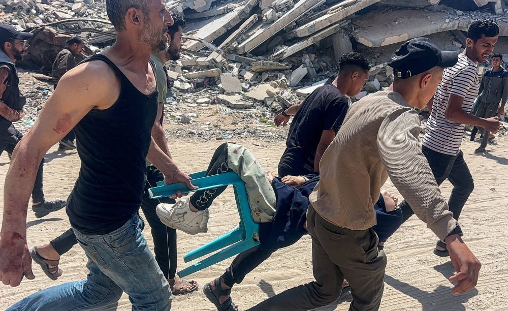 Palestinians carry a victim after an Israeli airstrike, in Gaza City, on Wednesday. REUTERS