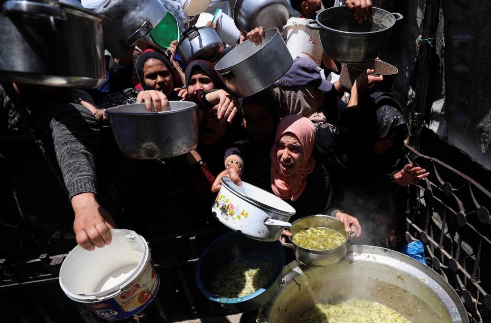 Palestinians receive food cooked by a charity kitchen, in Beit Lahia, northern Gaza Strip, yesterday