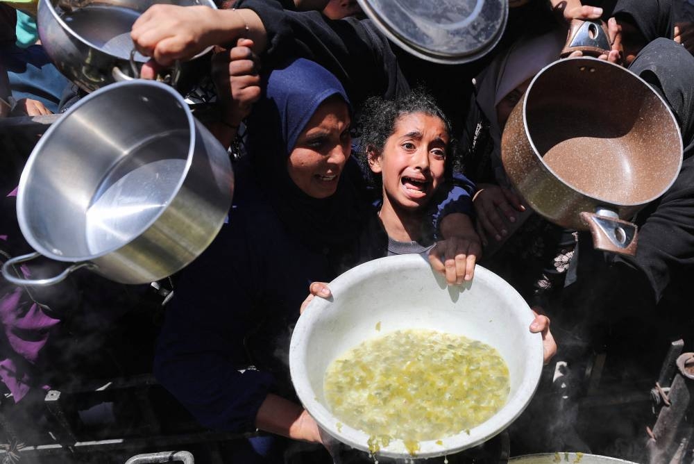 A girl cries as she wait to receive food cooked by a charity kitchen, in Beit Lahia, northern Gaza Strip. – Reuters